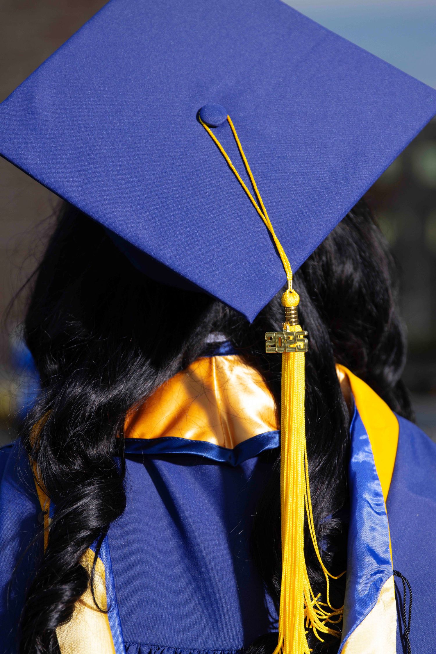 A graduation cap with gold tassel shown in multiple angles against a blue background.