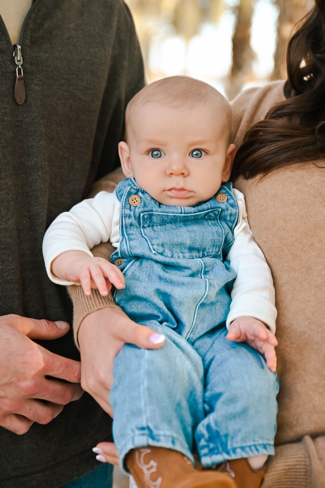 Close-up details of a baby wearing denim overalls and white shirt.
