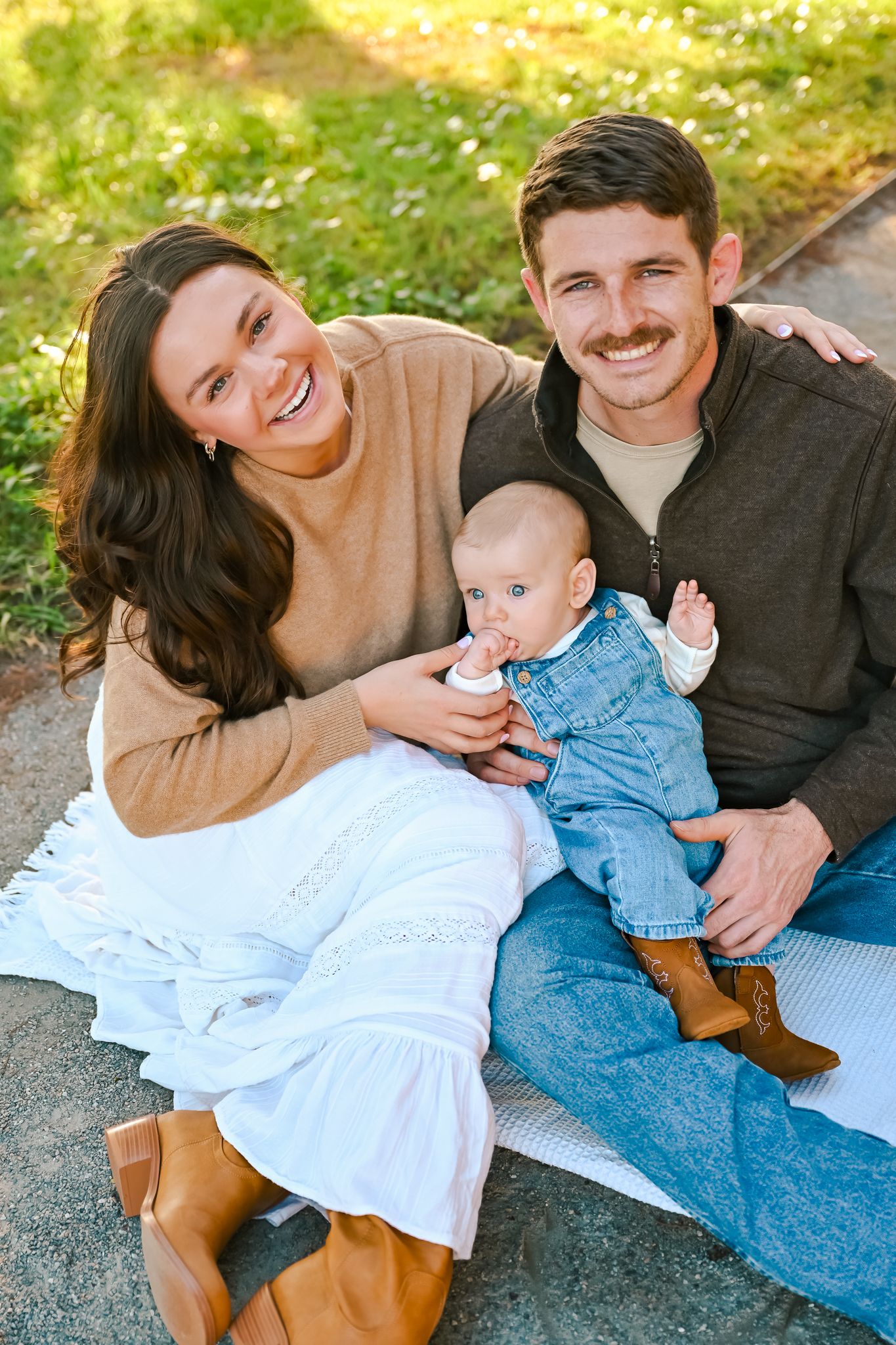 A family shares joyful moments together on a blanket during an autumn photoshoot.