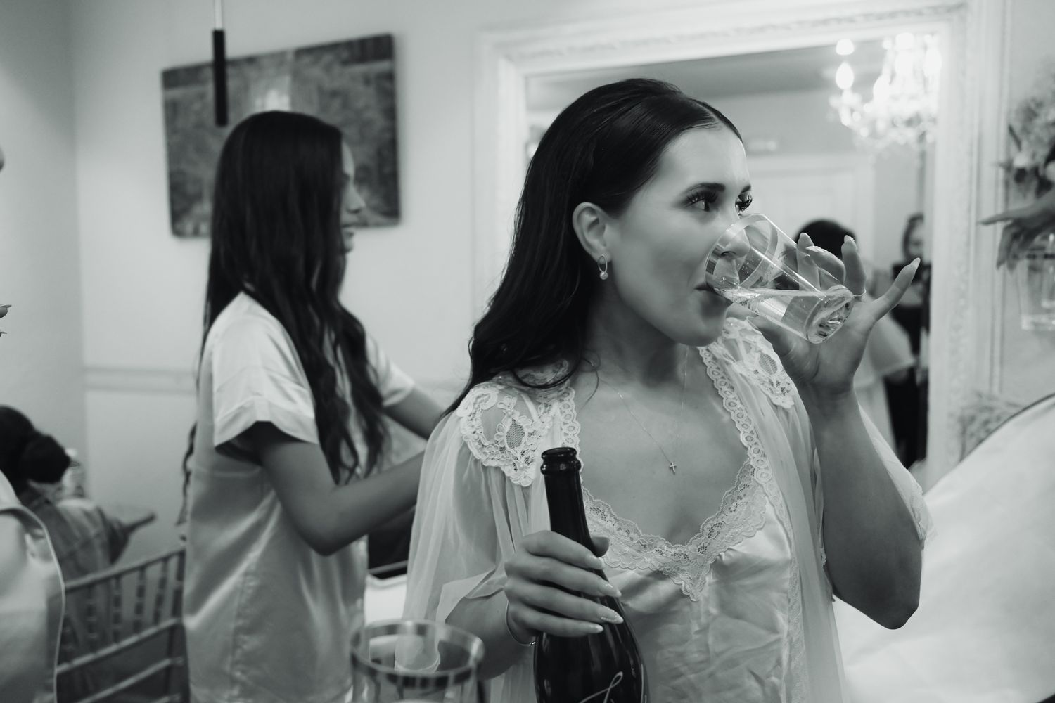 Black and white photo of a bride in lace robe drinking champagne at a wedding preparation celebration, Bakers Ranch Parrish Florida.