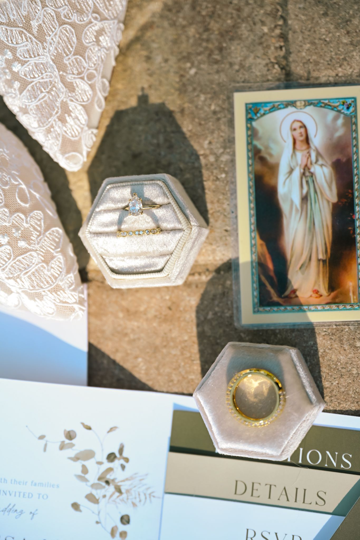 Bakers Ranch, Wedding flat lay with engagement ring in velvet box, lace fabric, Virgin Mary prayer card, and elegant invitation suite.