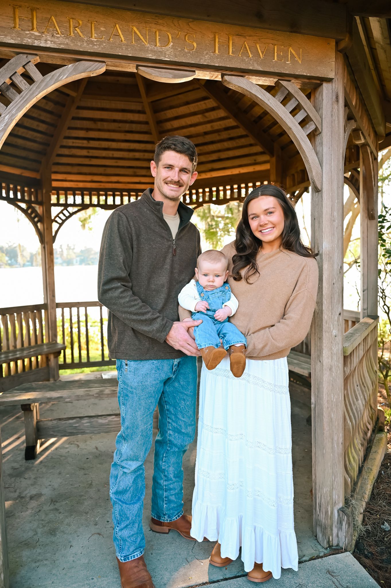 A family portrait session under a wooden gazebo labeled Harland's Haven.