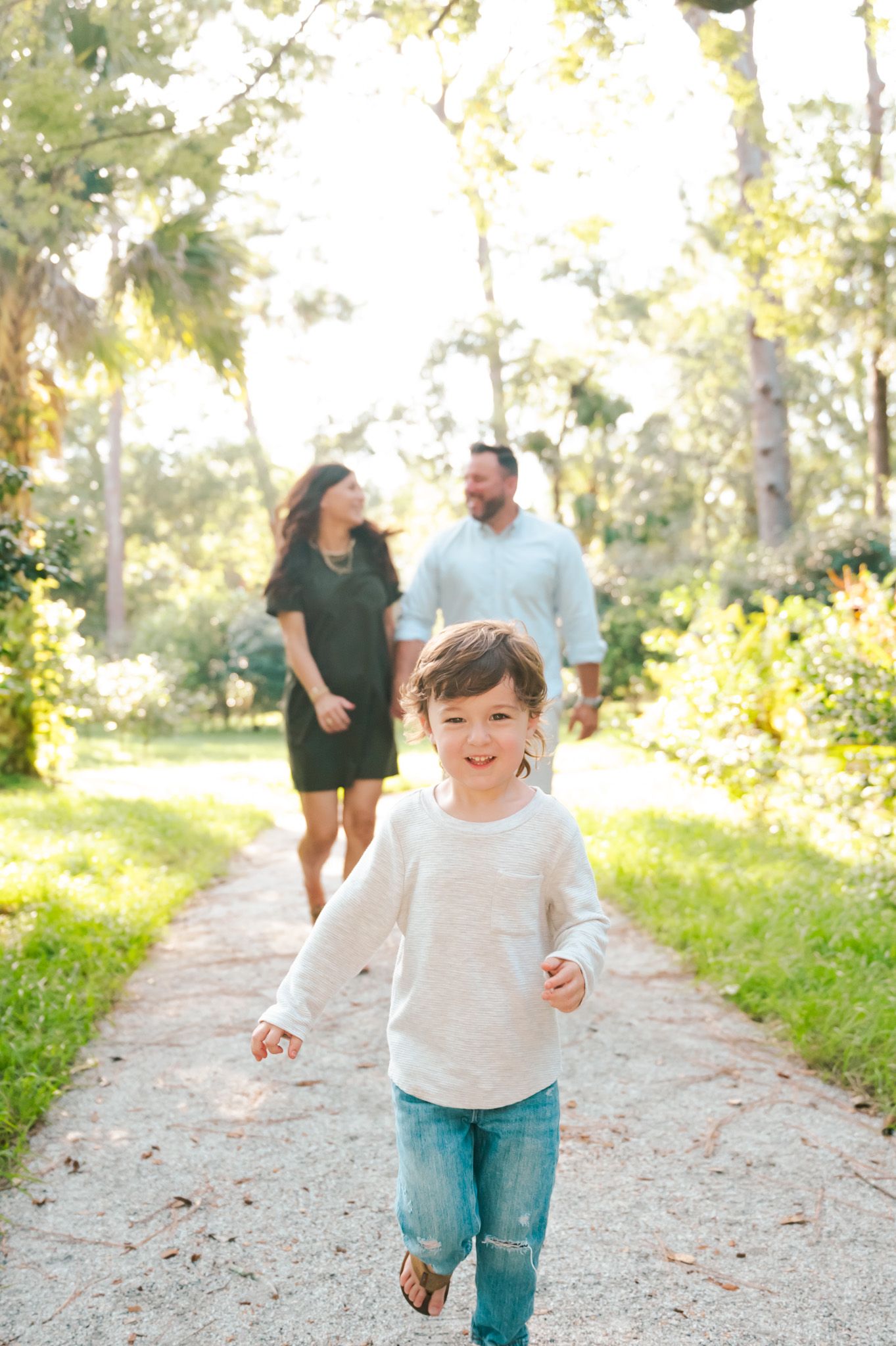 Children running and playing on a sunlit nature path with adults in background.