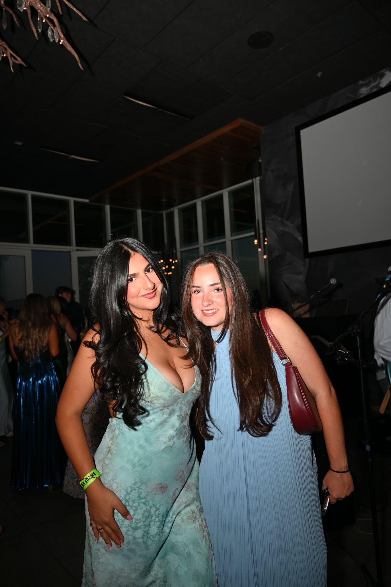 Two young women in elegant blue dresses posing together at a formal evening event.
