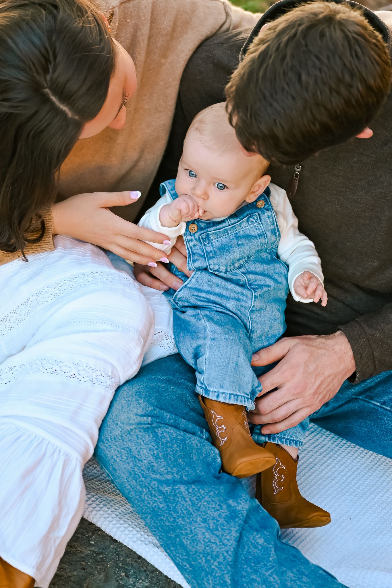 An intimate moment between family members lying on a blanket outdoors.