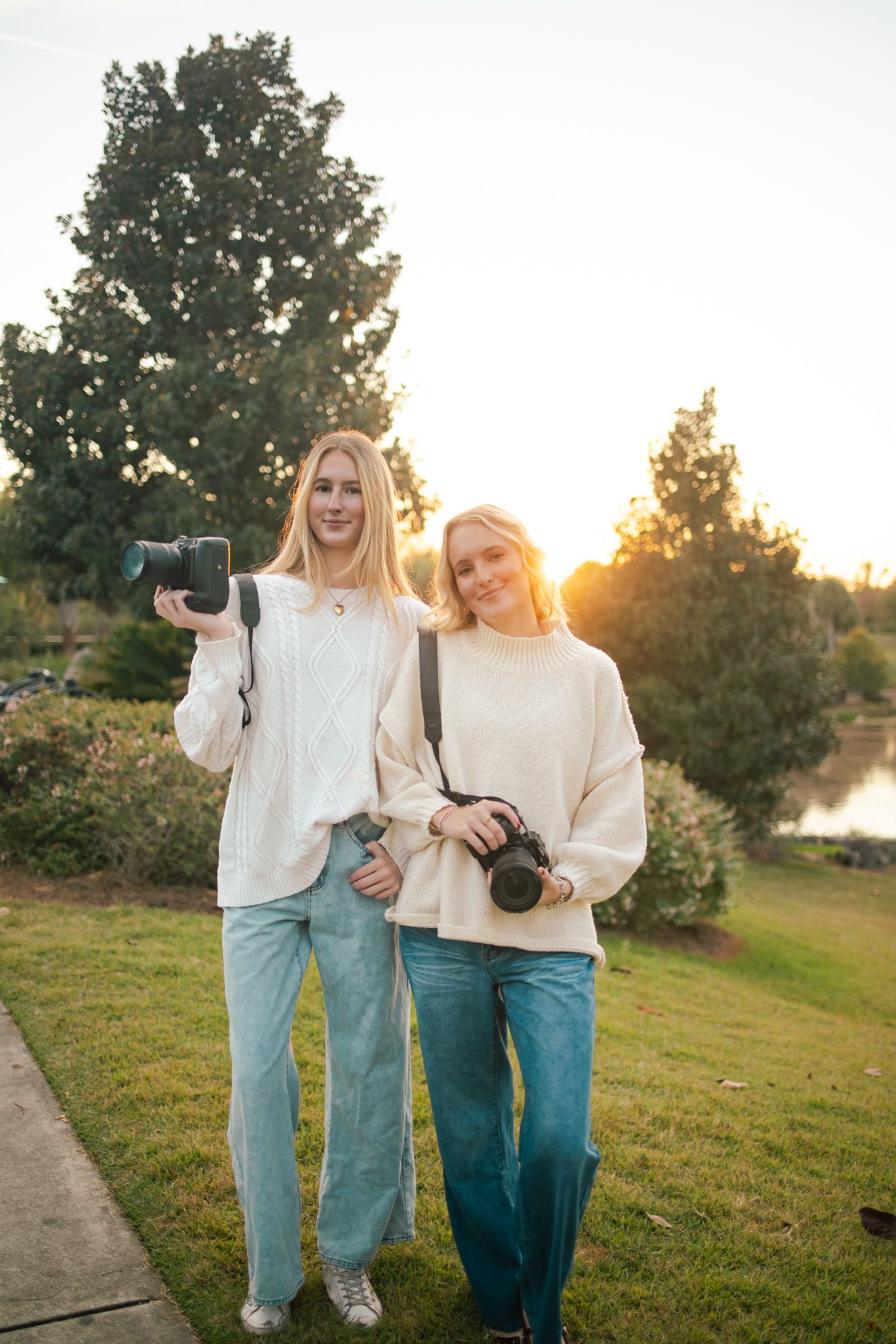 Bella and Ava, the sister duo behind SP, in matching outfits laughing and taking pictures together outdoors at golden hour.