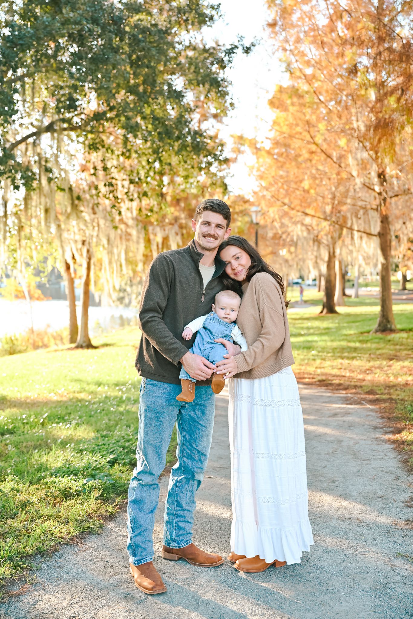 A family enjoys a warm autumn day together on a tree-lined path.