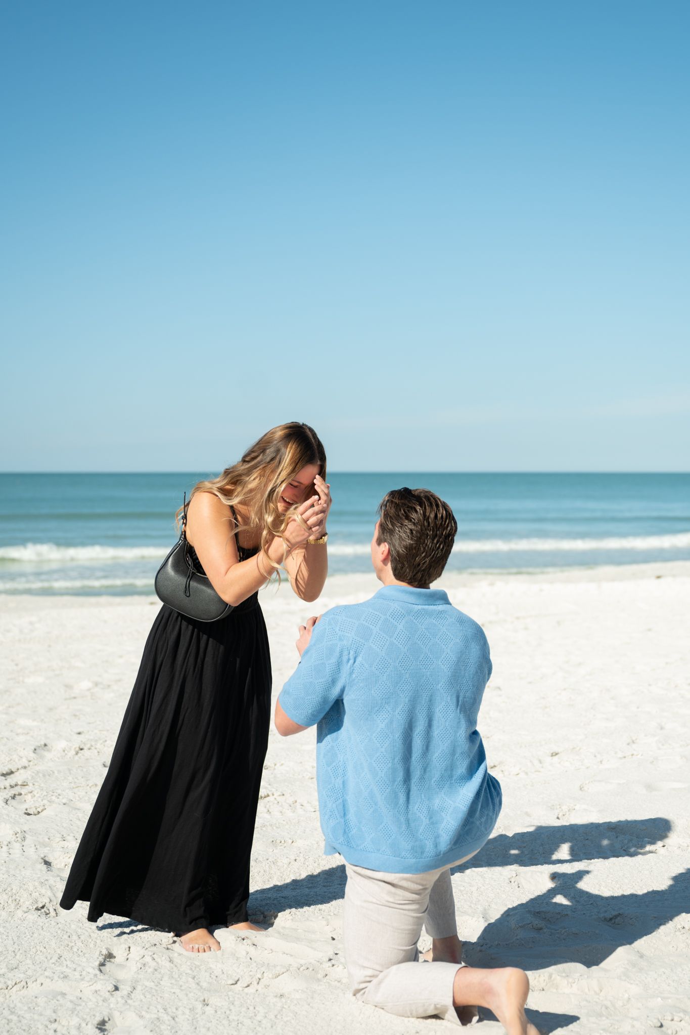 Two people sharing an intimate engagement while sitting on a pristine white sand beach.