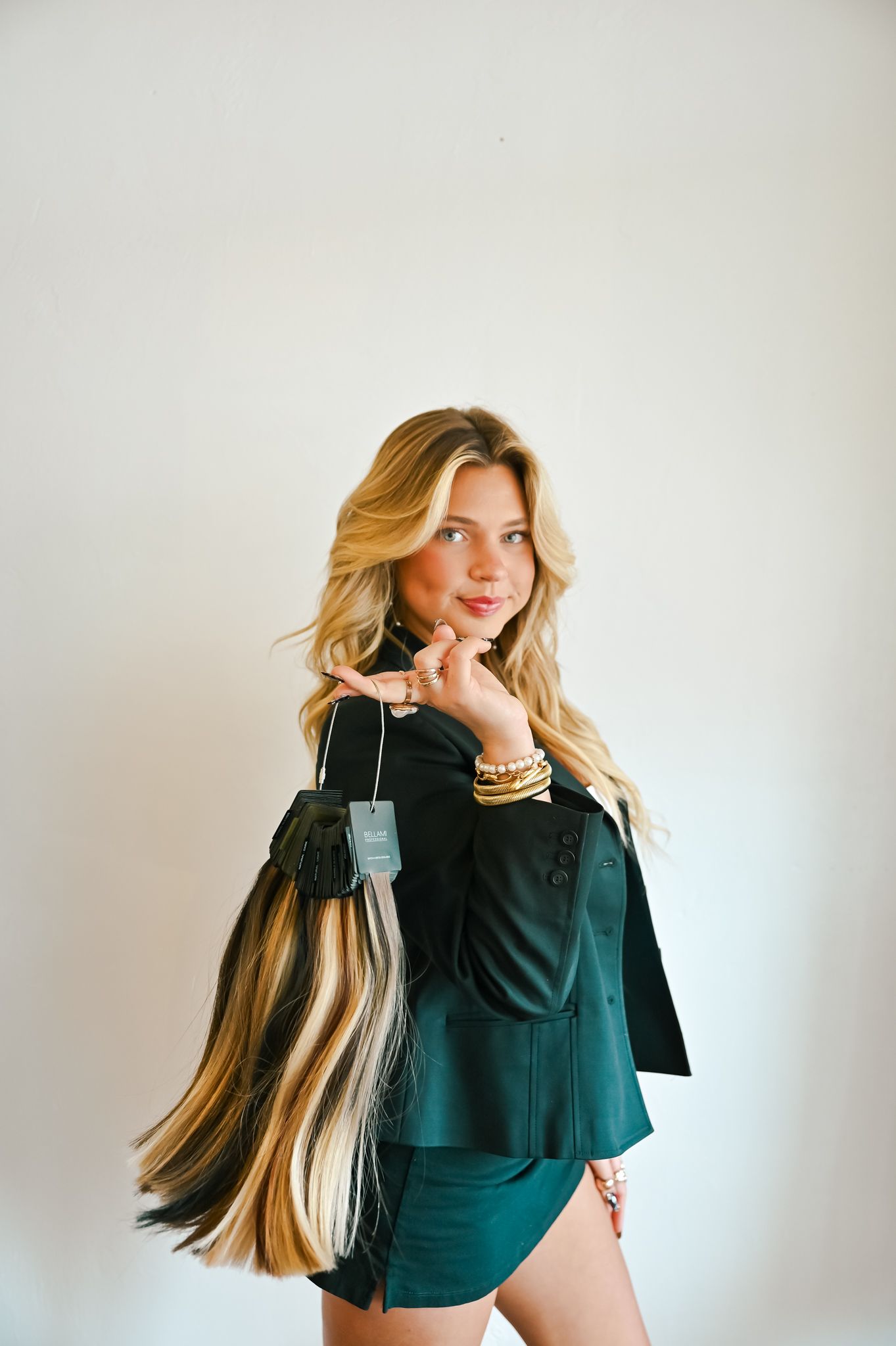 Fashion model wearing dark teal top with flowing blonde hair against white background in artistic photo series.