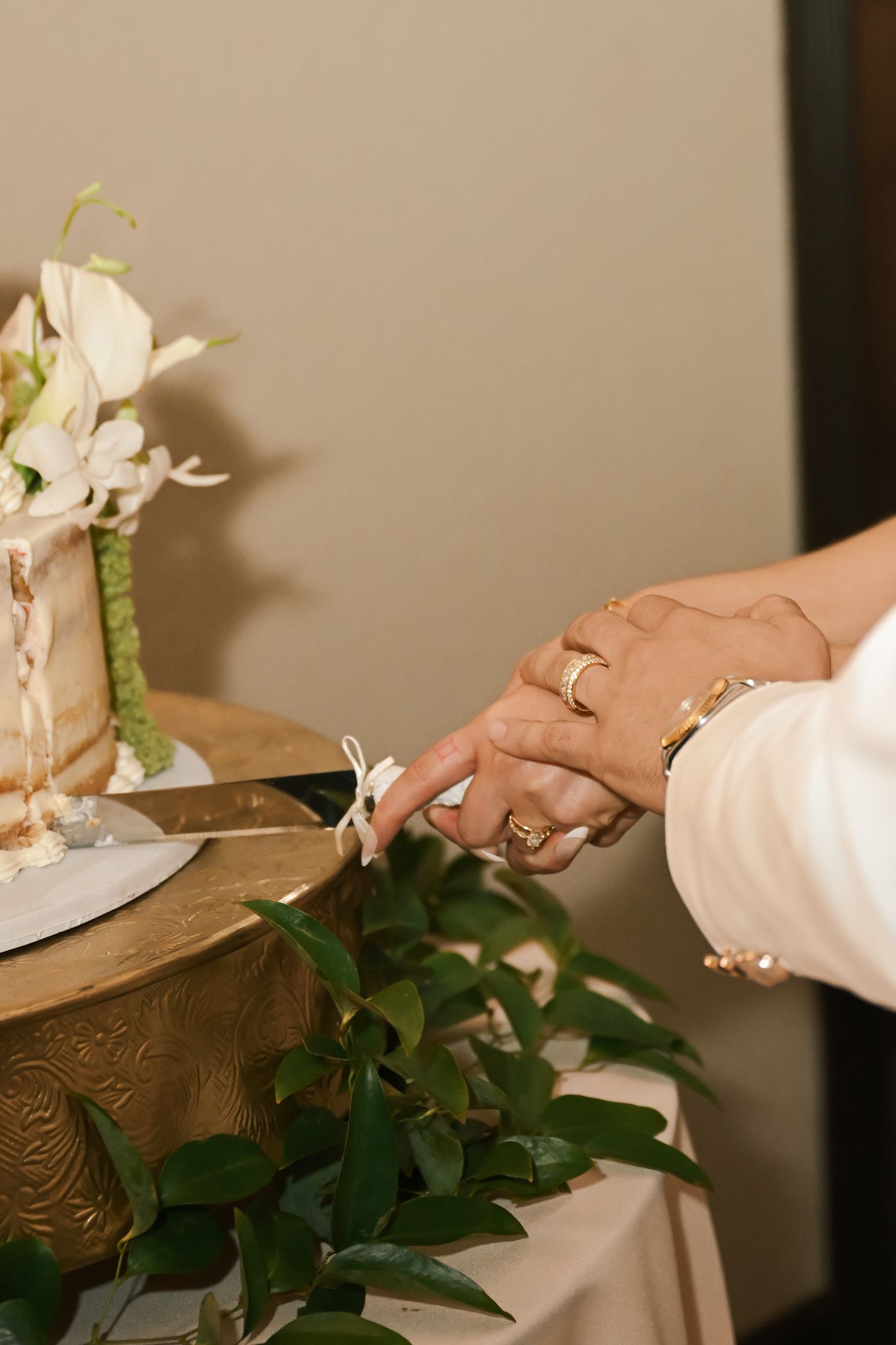 A hand arranges delicate white flowers and green foliage on a wooden surface during a floral arrangement session.