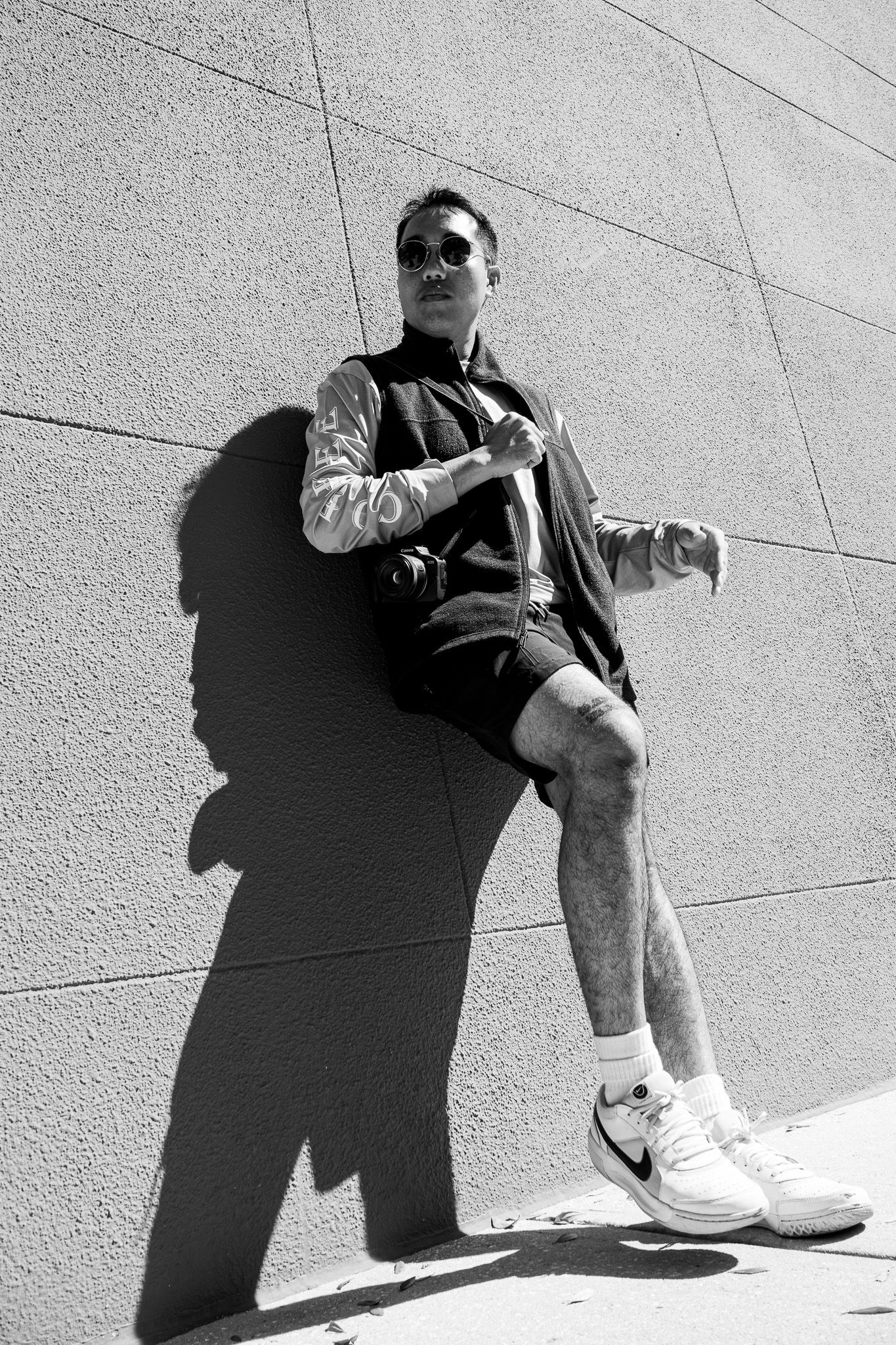 Black and white sequence showing a person sitting against a wall in dramatic shadow.