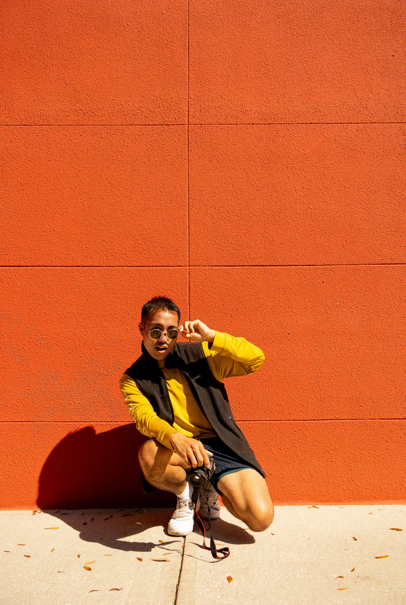 Person in sunglasses poses against vibrant orange wall in dynamic sequence.