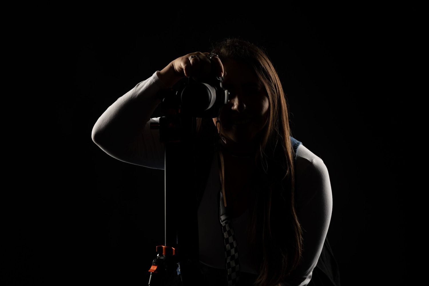 A silhouetted figure stands in dramatic lighting with a dark background, creating a moody and artistic portrait.