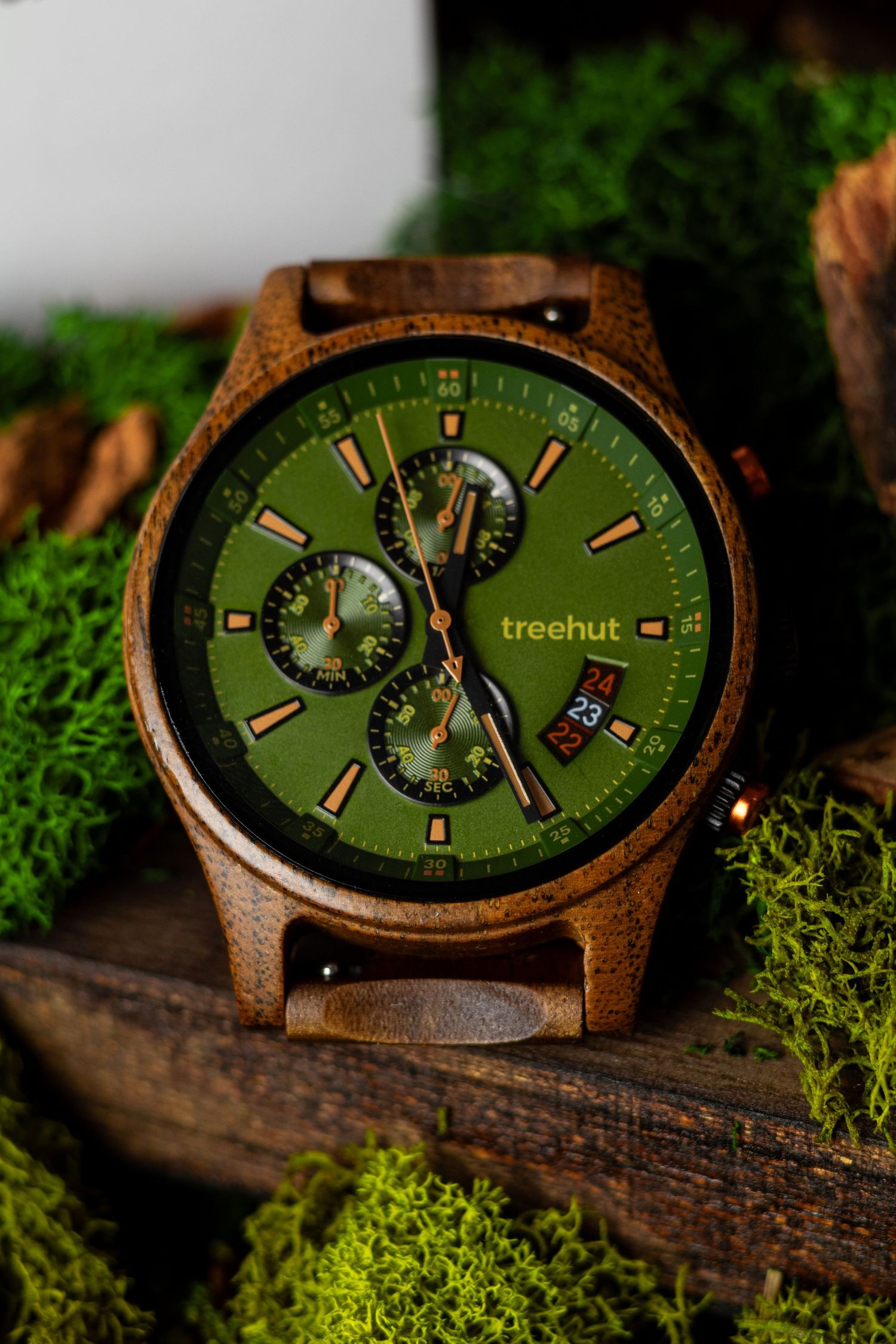 Treehut wooden watch with green dial displayed on mossy log in natural lighting.