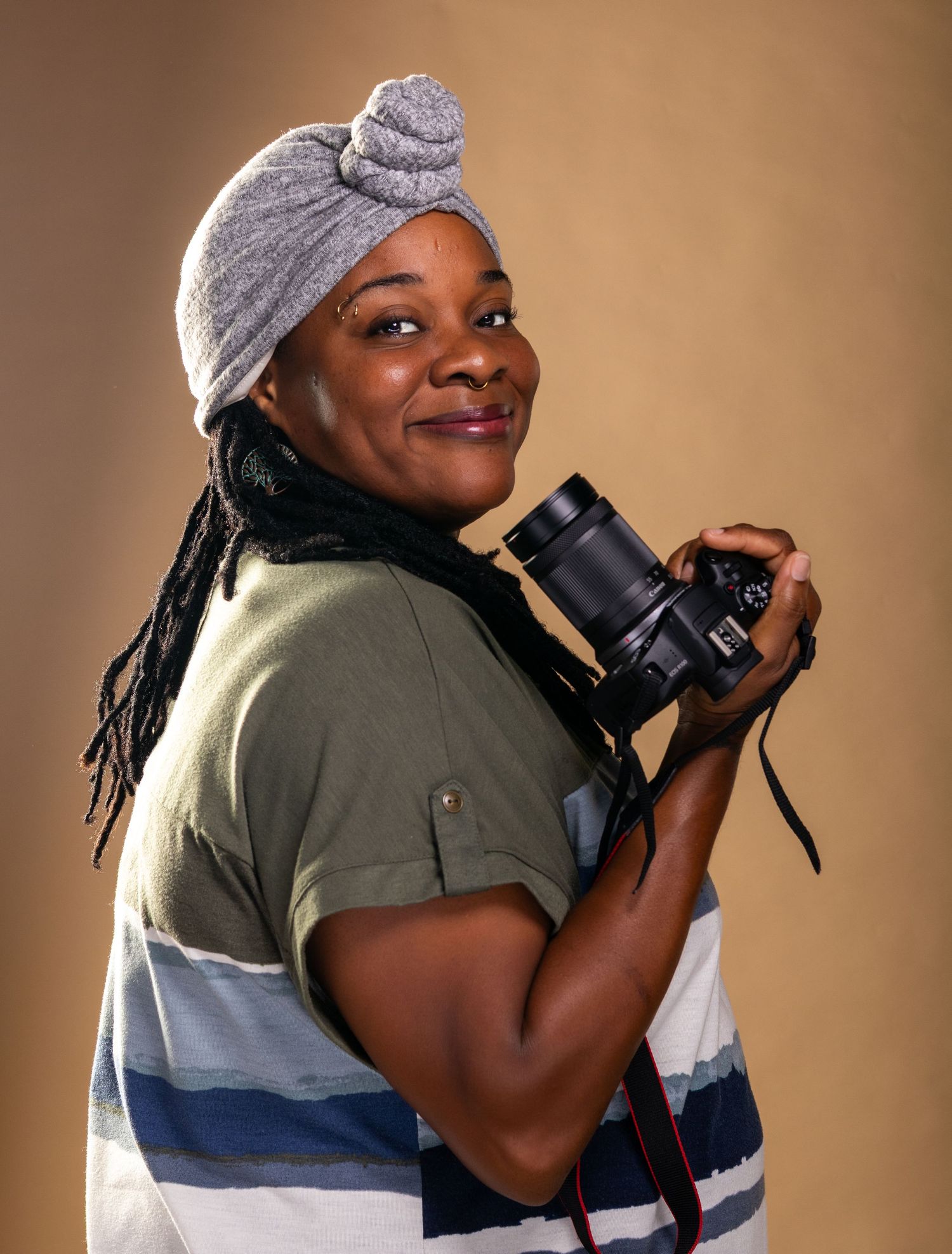 A photographer in a gray beanie and olive shirt demonstrates different camera holding positions against a brown backdrop.