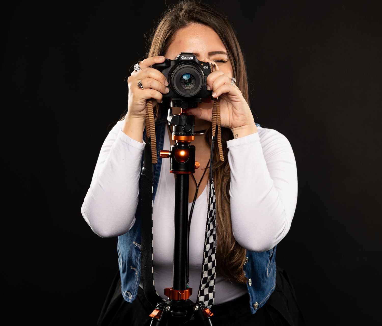 Close-up shot of photographer using professional camera against dark background.
