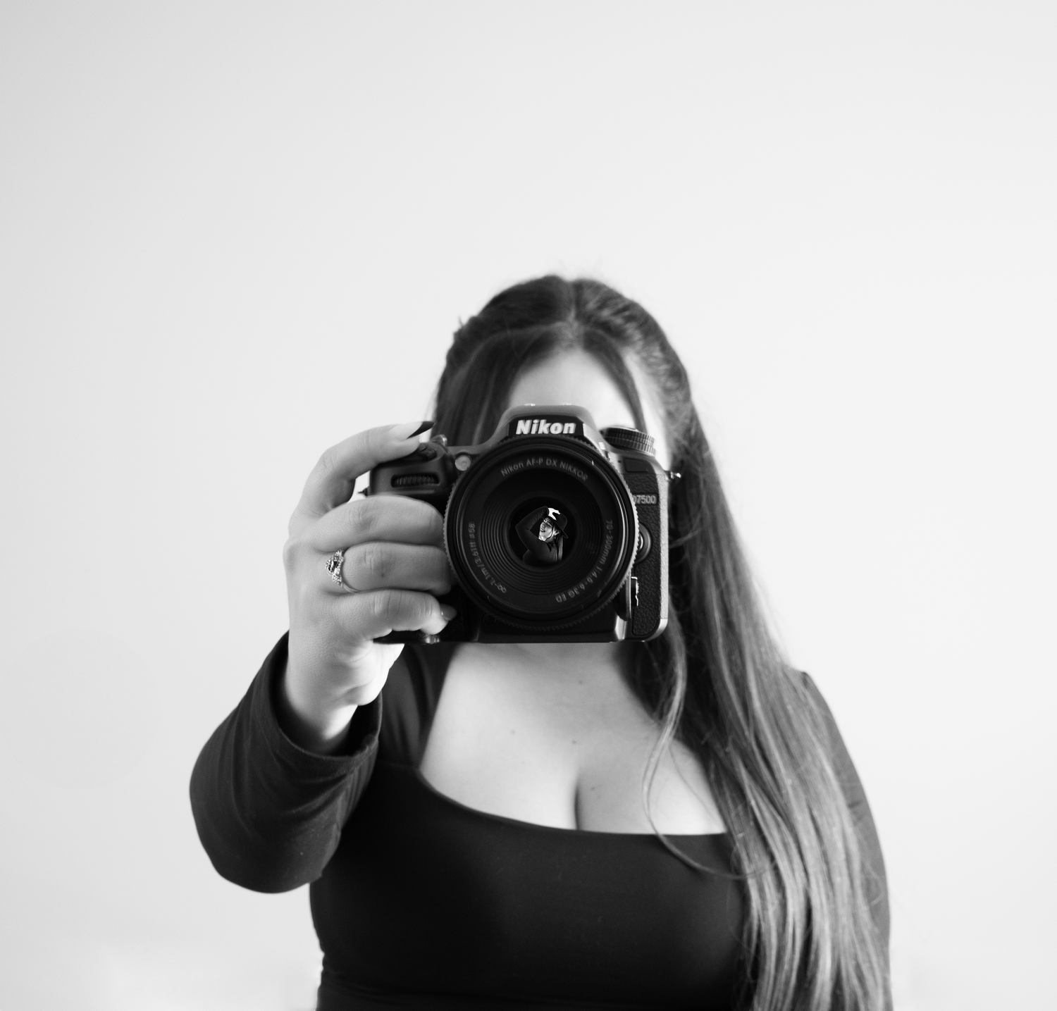Black and white portrait of photographer holding Nikon camera.