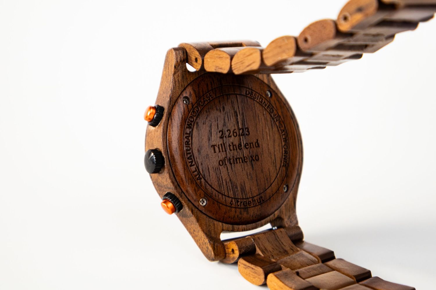 Detail shot of wooden watch case back showing natural grain and metal buttons.