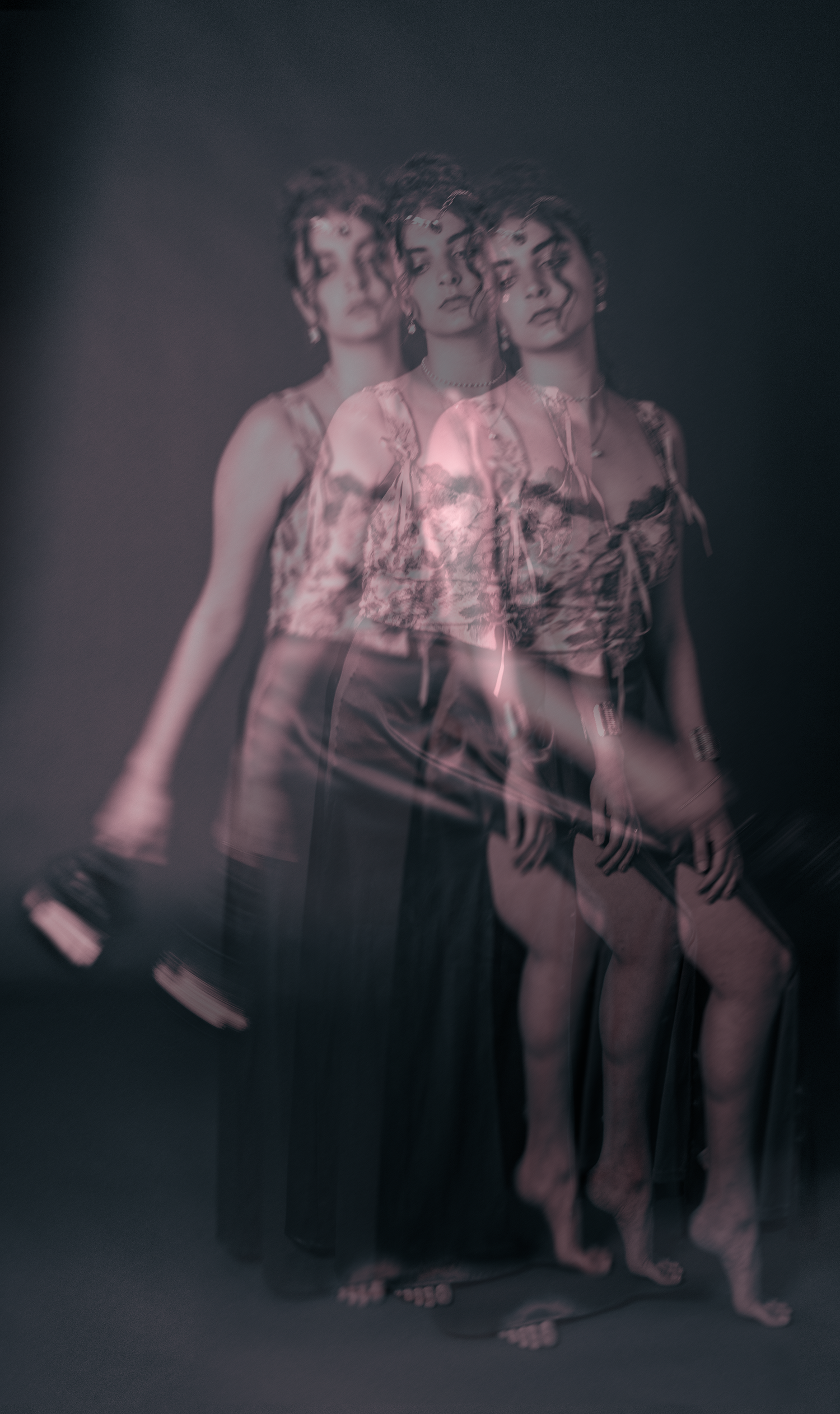Multiple exposure photograph shows motion sequence of a figure moving in a dark, artistic composition.