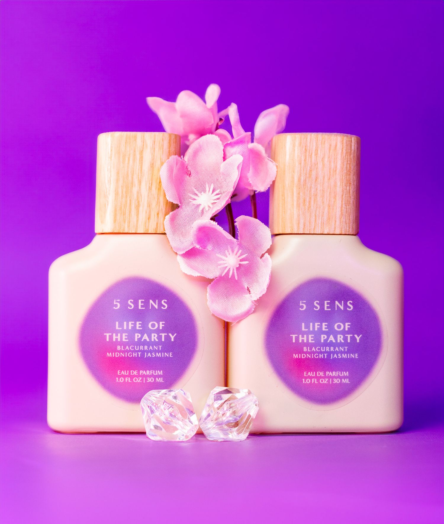 Pink beauty product containers against a vibrant purple background with delicate cherry blossoms. Product photography