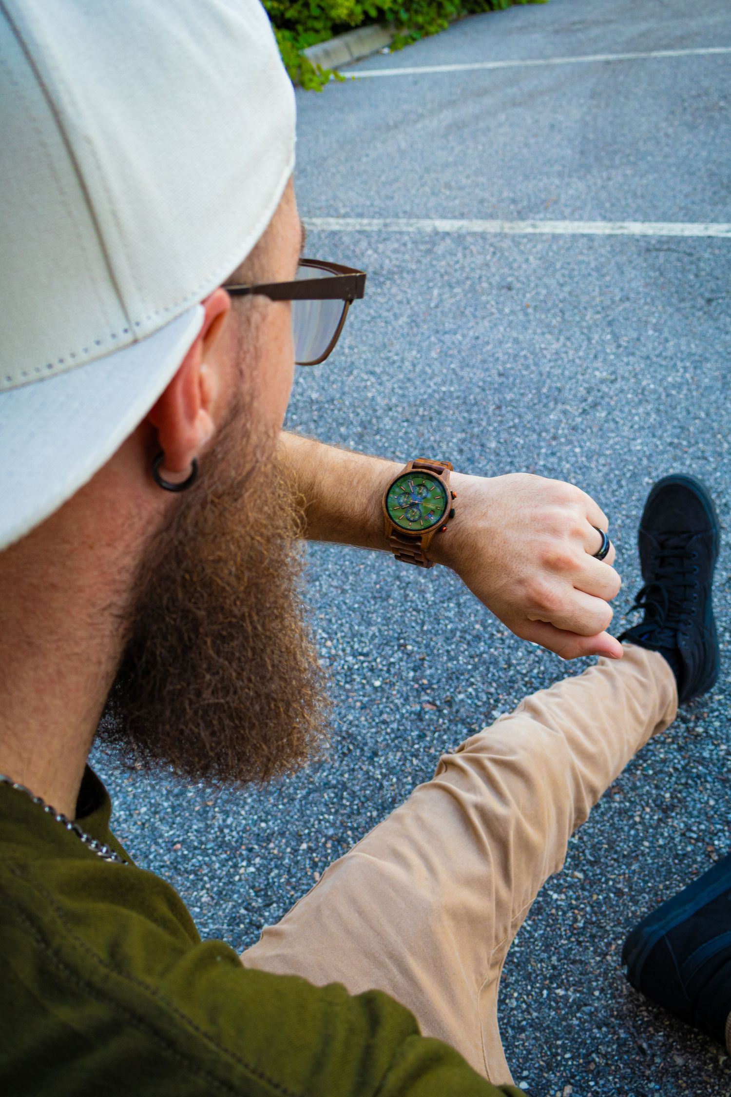 Close-up of wooden watch with green face shown at different angles on wrist.