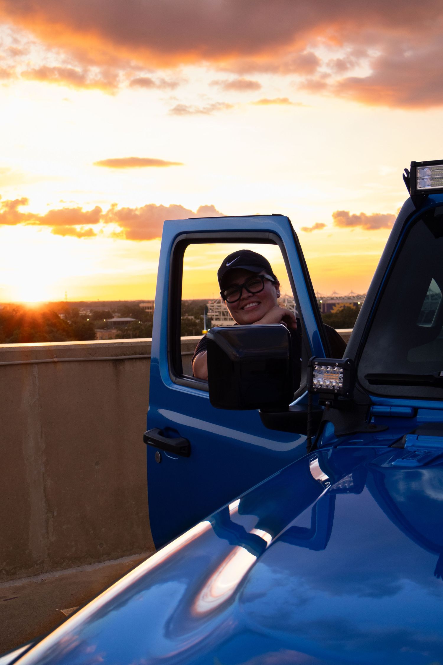Blue truck captured at sunset with dramatic orange sky.