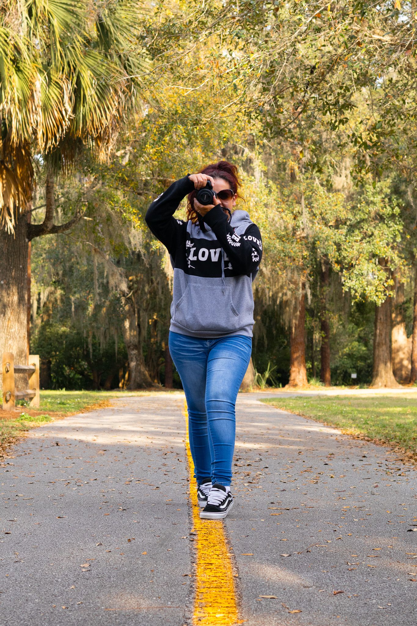 Figure walking down a palm-lined path with yellow line marking.