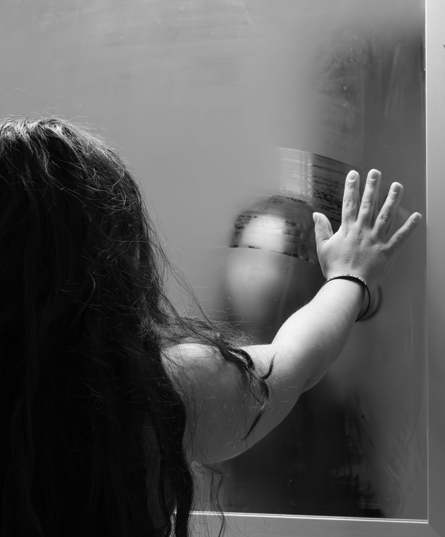 A dramatic sequence showing a person pressing their hands against glass in black and white, creating an eerie atmosphere.