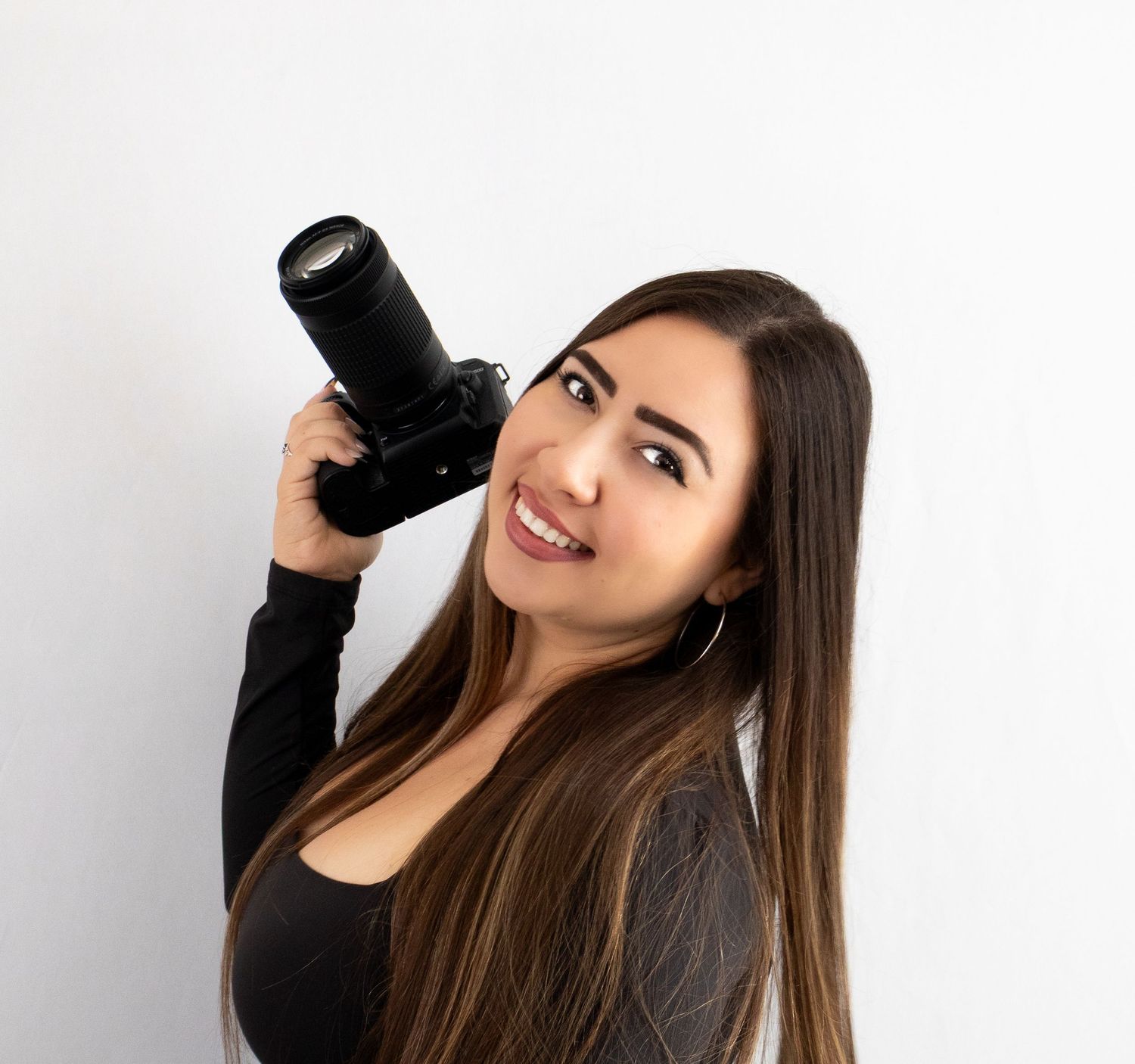 Photographer holding professional camera against white background.