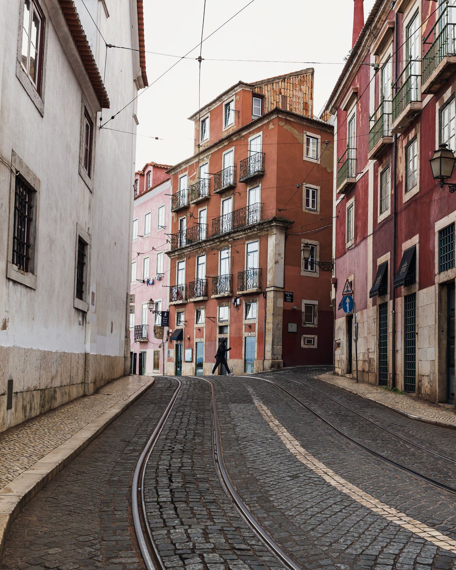 Curved cobblestone tram street lined with colorful historic buildings in Lisbon, Portugal.