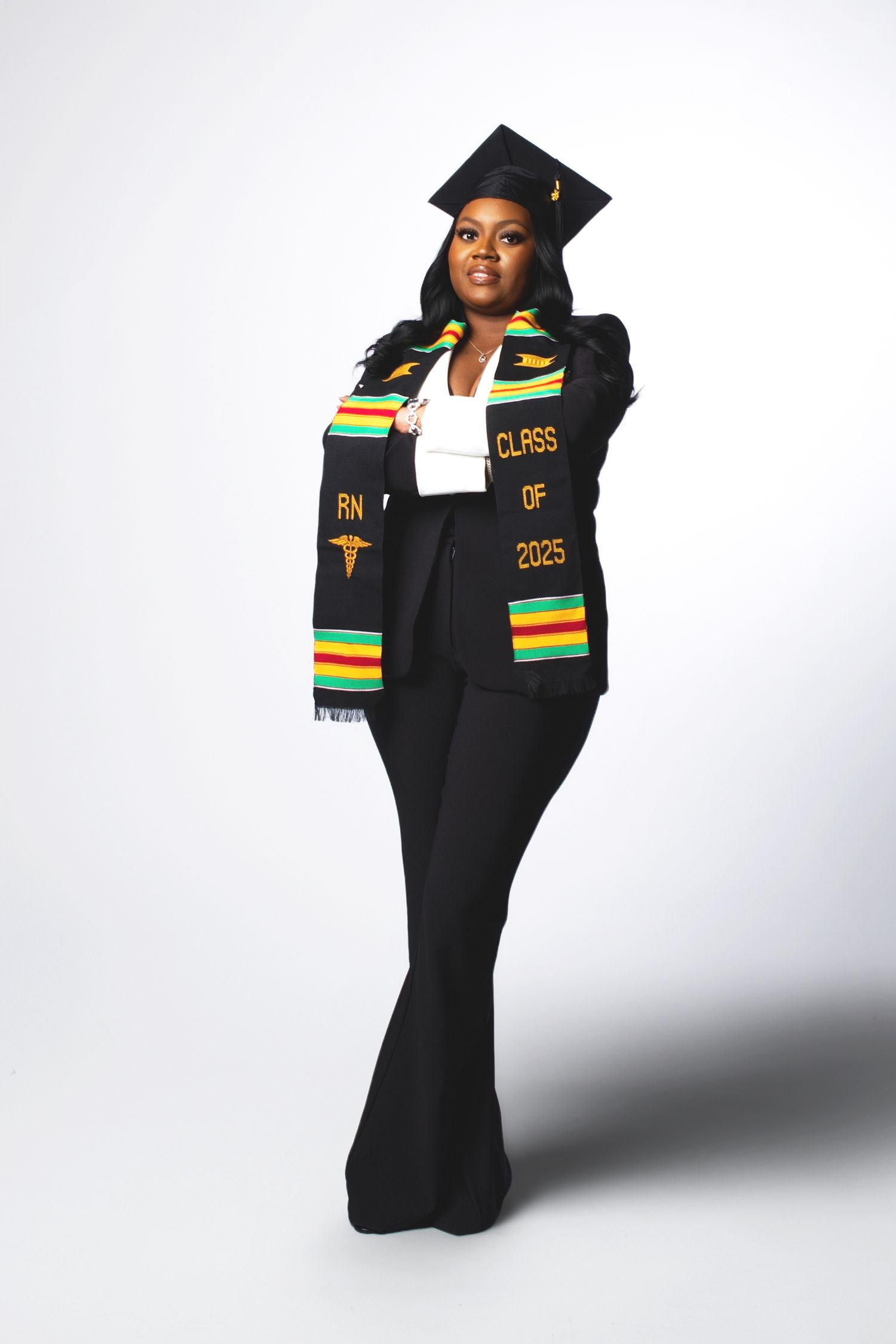 Nursing graduate in Class of 2025 RN kente stole and black cap poses for professional photo.