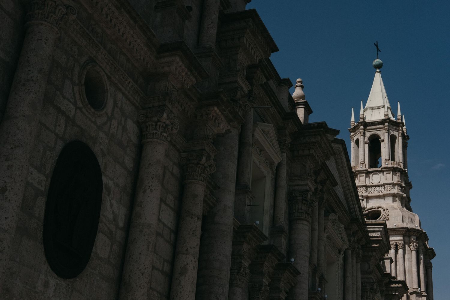 Ornate colonial church architecture with bell tower against deep blue sky in Arequipa.