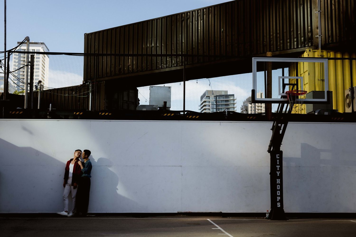 Urban couple portrait against industrial white wall with overhead architecture.