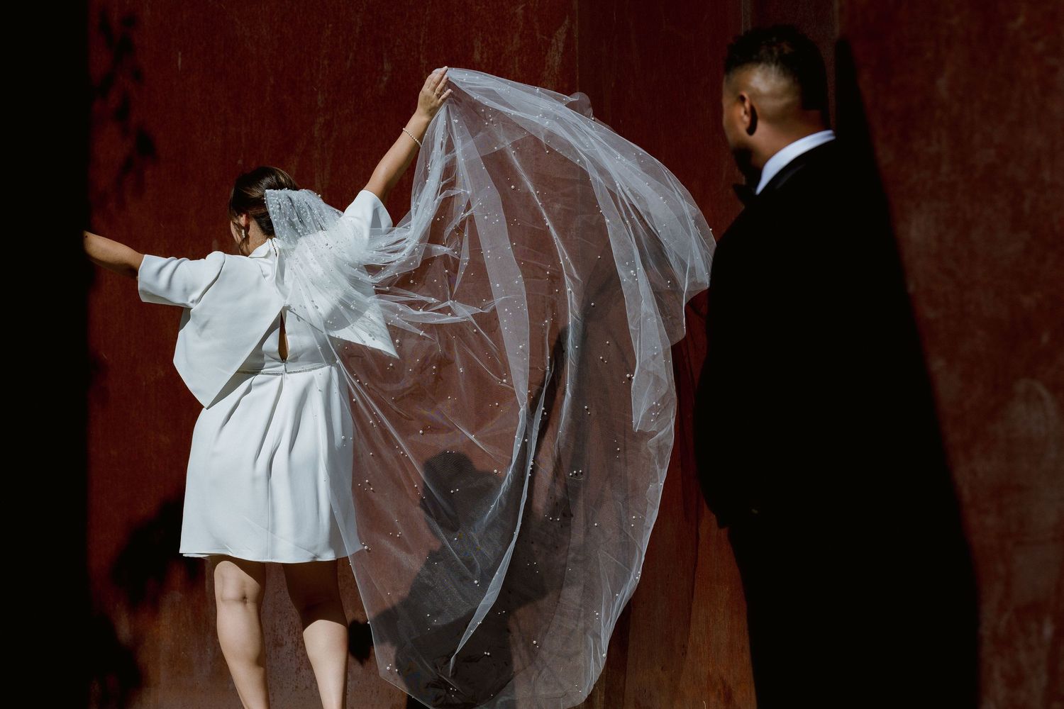 Wedding themed photos with flowing white dress and veil against dark red background.