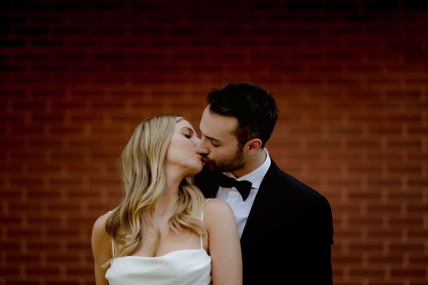 A romantic moment between a couple against a brick wall background at their wedding.