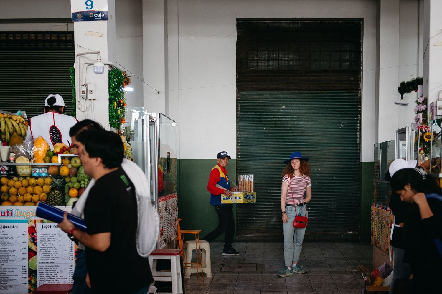 Long white corridor with closed shop doors and minimal lighting.