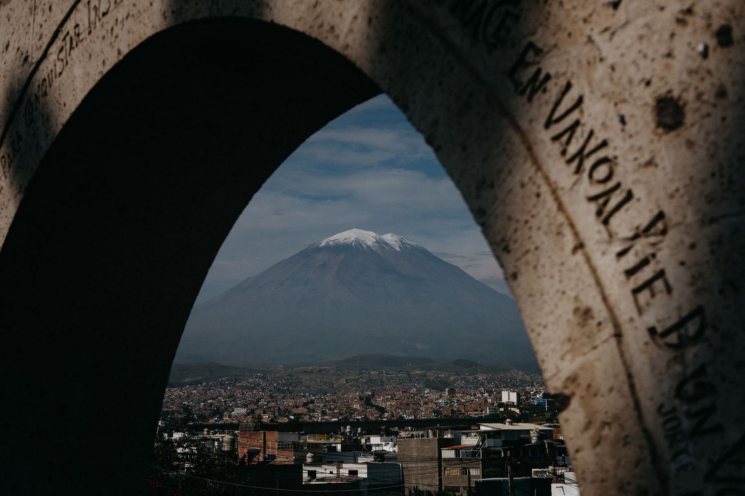 Framed view of Misti volcano through stone arch overlooking city of Arequipa.