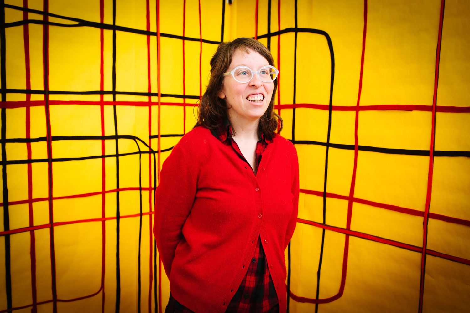 Candid portrait against yellow geometric background with bright red sweater.