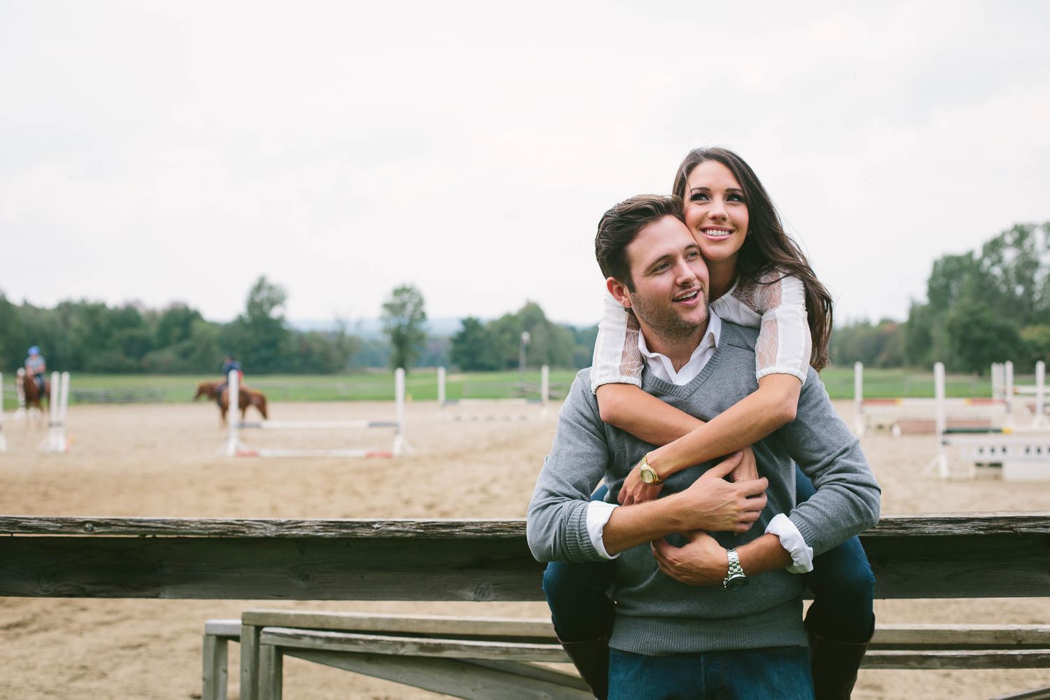 A joyful couple embraces while sitting on wooden bleachers outdoors.