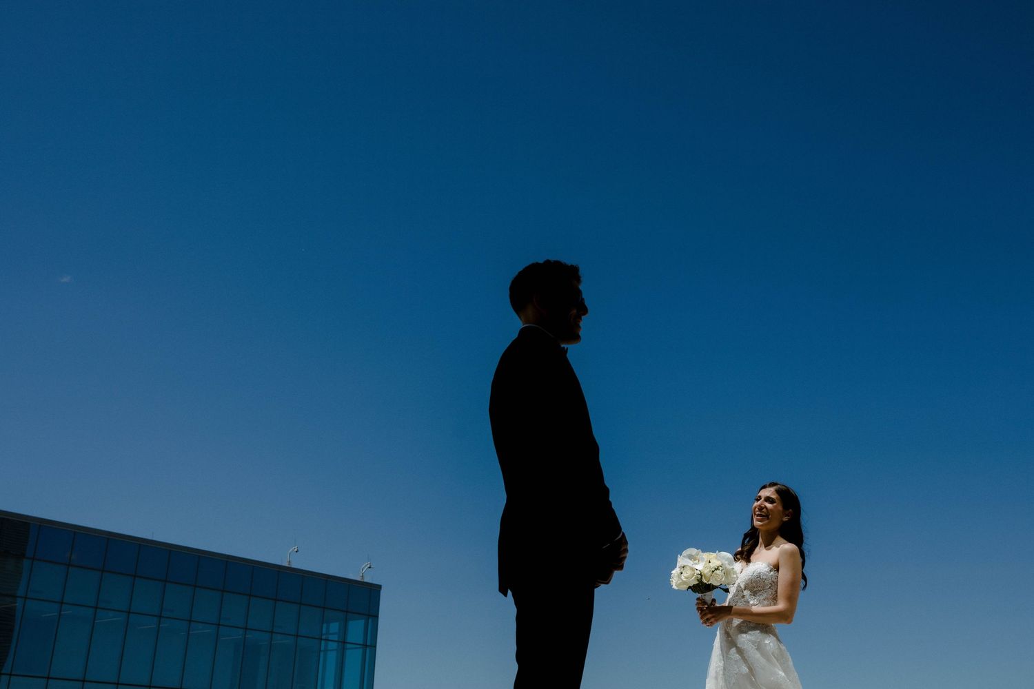 Dramatic silhouettes against a vibrant blue sky during an outdoor photo session.
