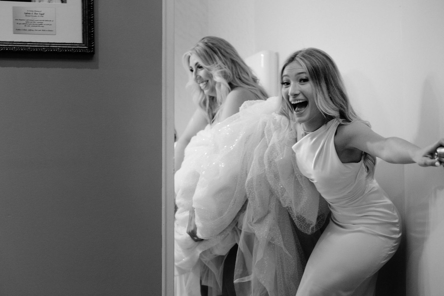 Two people share an energetic candid moment filled with laughter and joy in their formal attire.