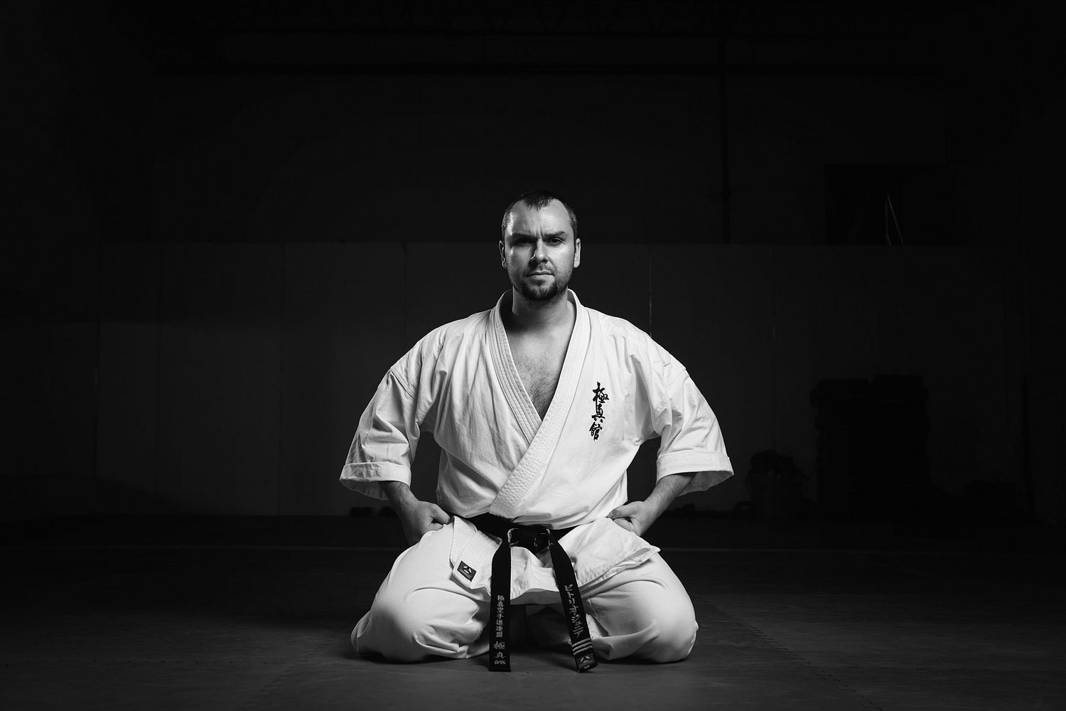 Black and white image of a martial artist in white gi sitting in meditation.