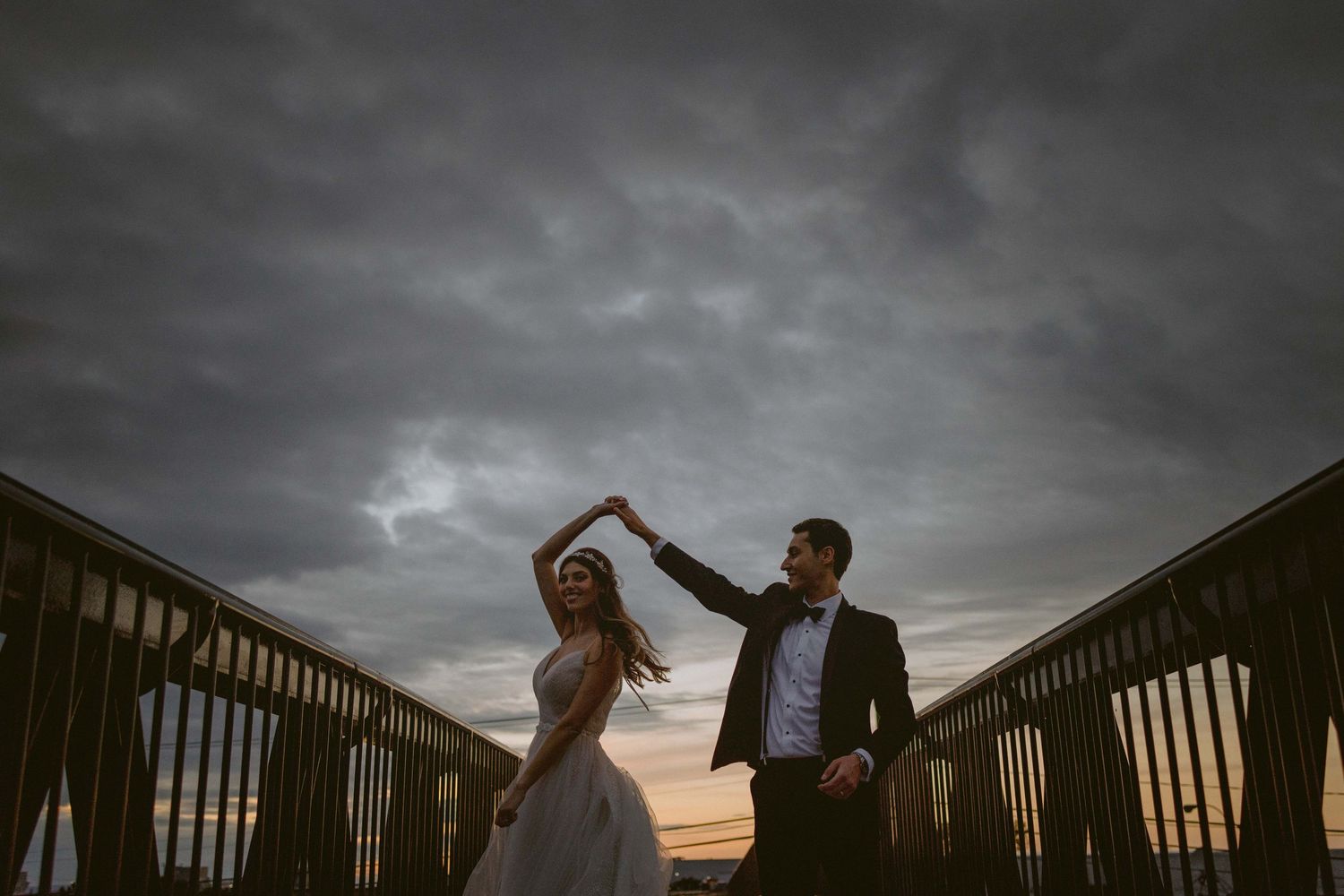 Dramatic storm clouds create moody backdrop for outdoor wedding portraits.