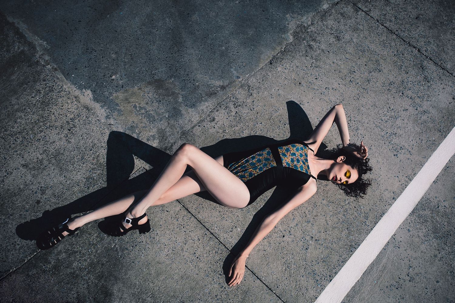 Fashion photo of person in black outfit lying on concrete ground.