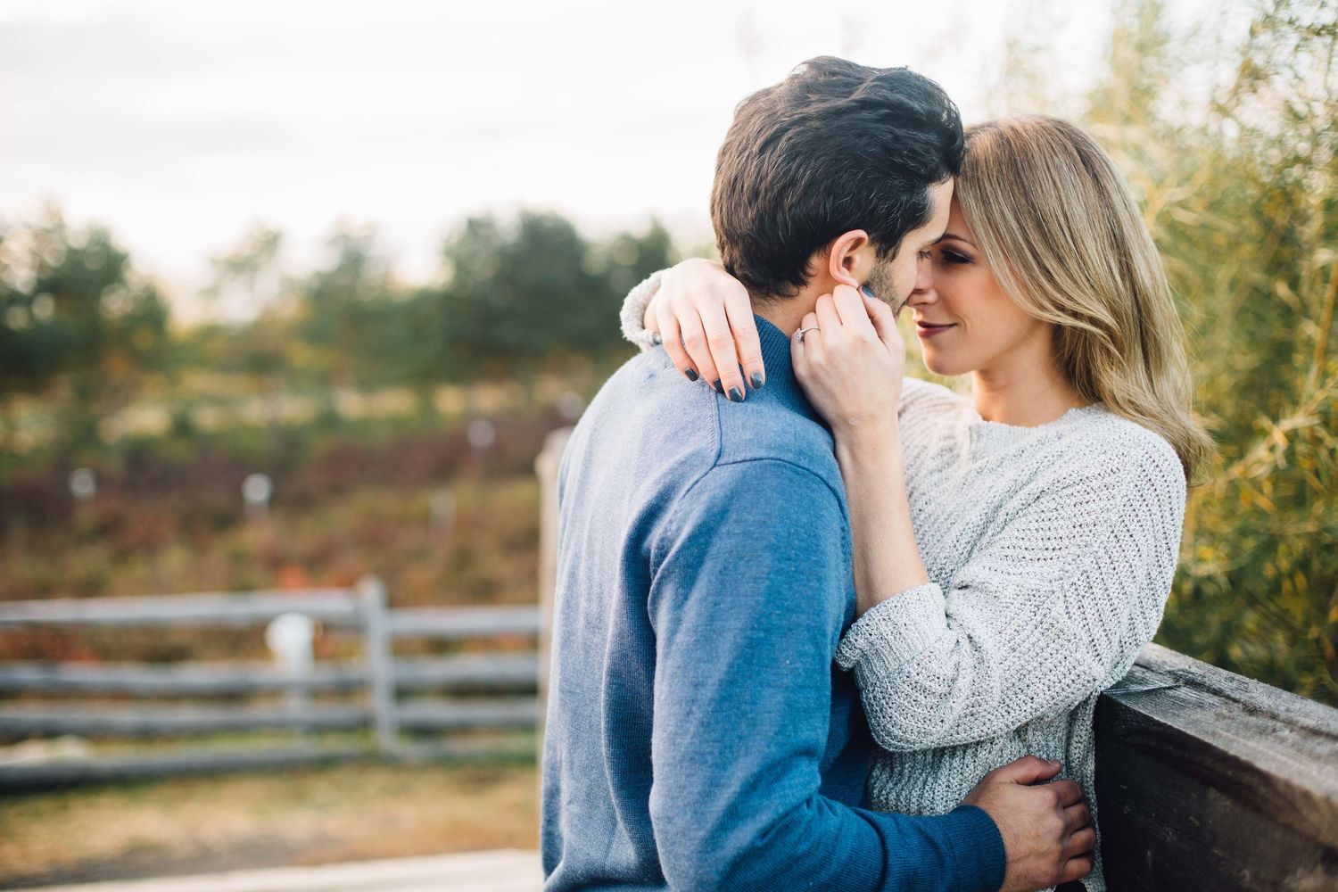 Intimate couple moment captured in warm light against rural fence background.