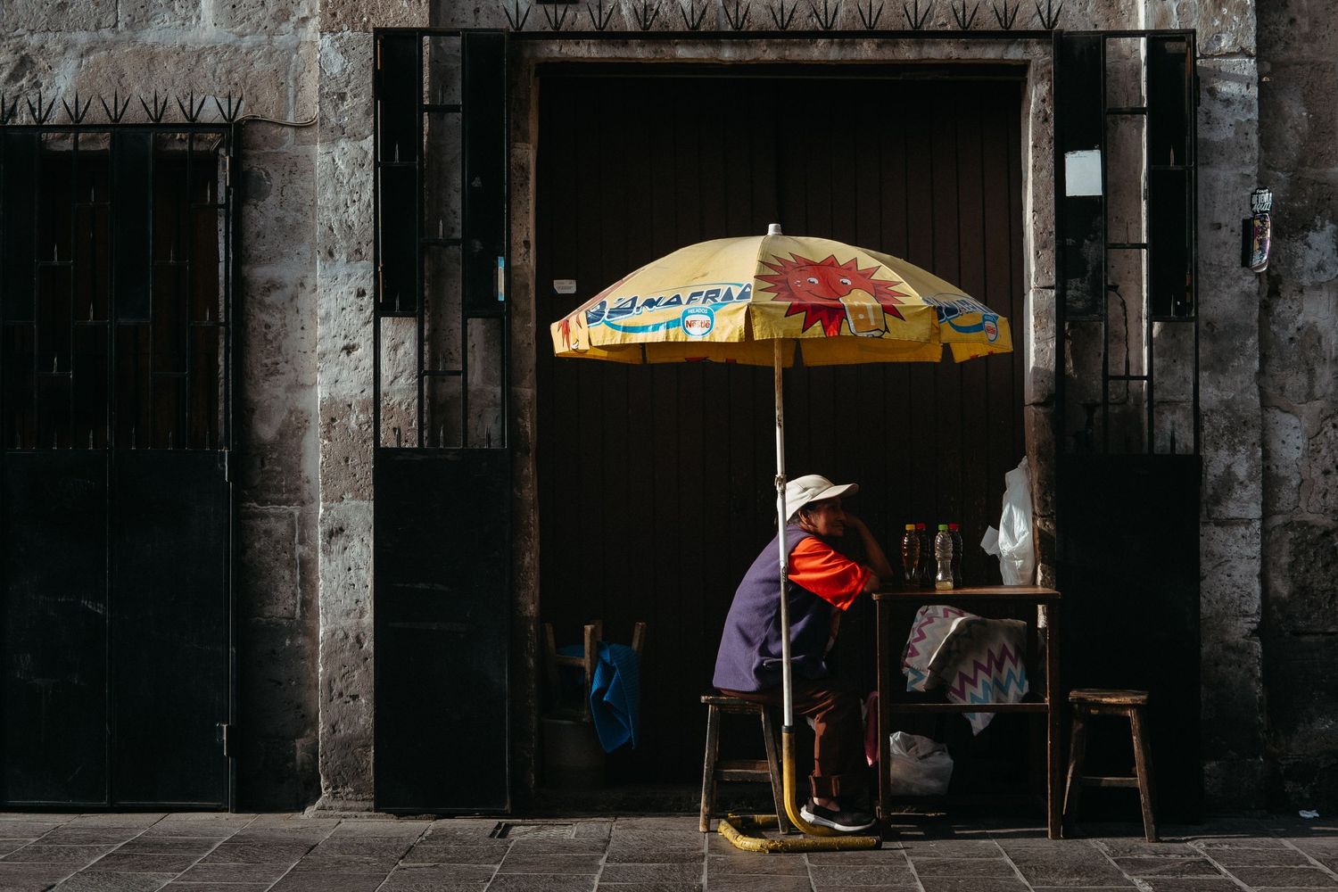 Dark stone colonnade with scattered yellow umbrellas creating atmospheric lighting.