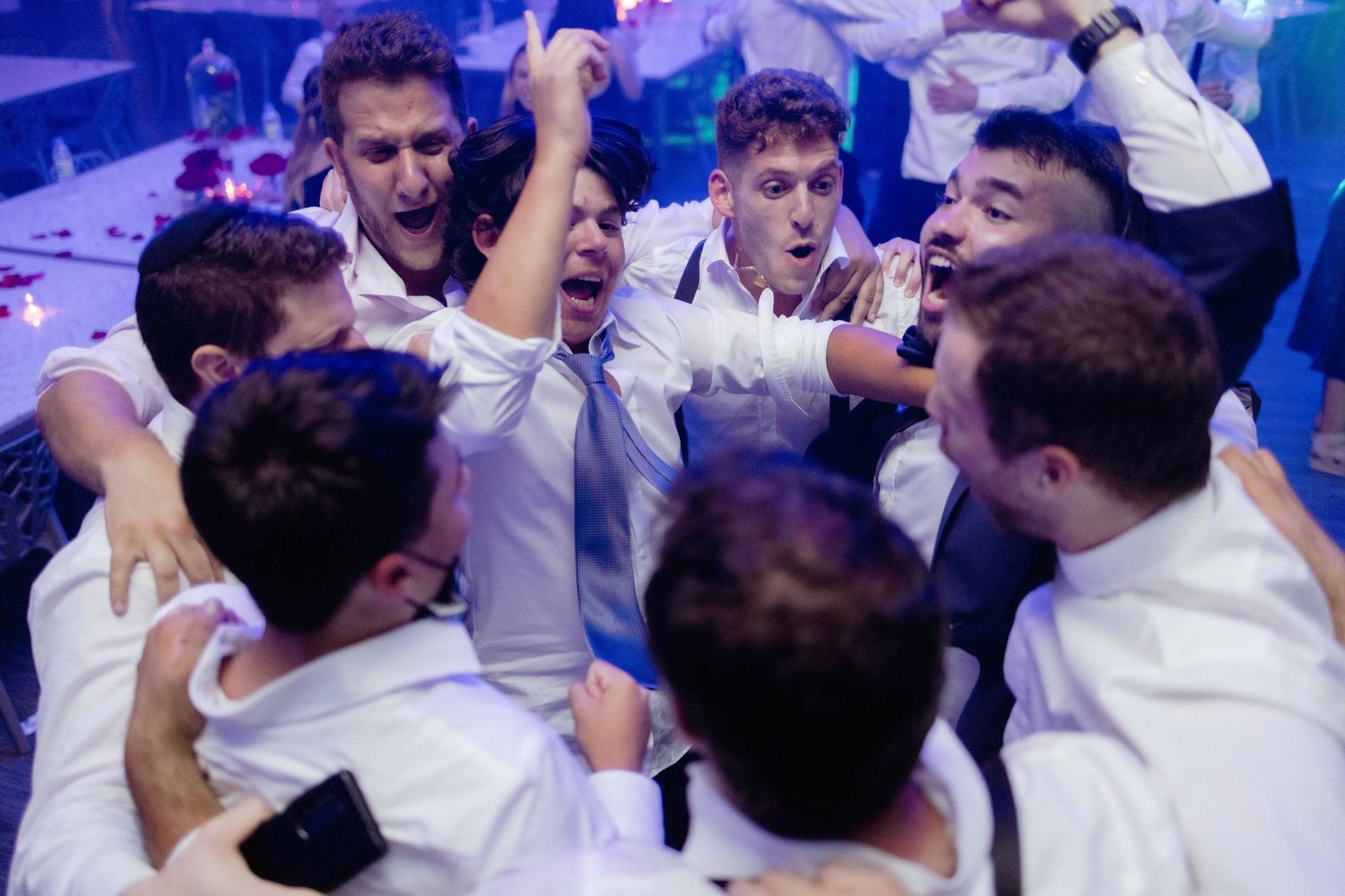 A celebratory crowd in white shirts raises their arms in excitement.