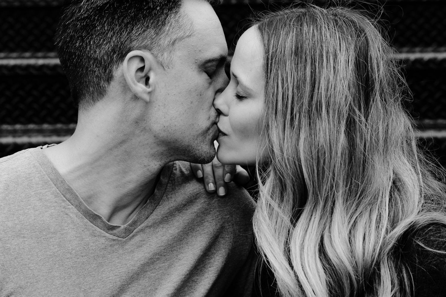 An intimate black and white portrait captures a couple's tender kiss.