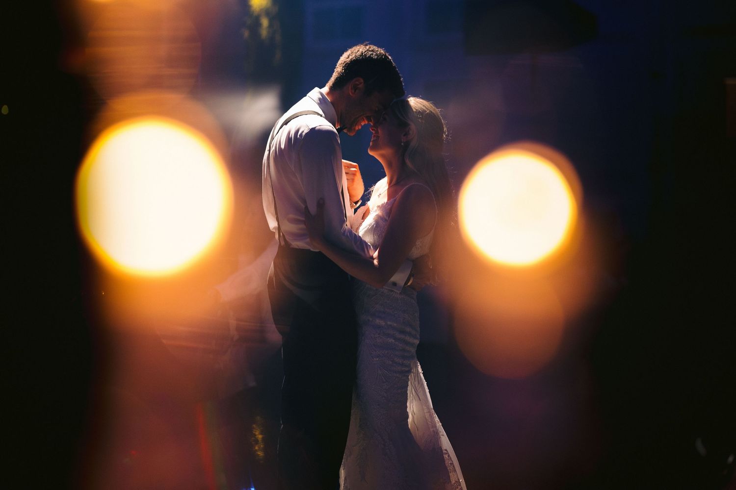 Romantic dance moment captured in dark lighting with glowing orbs in background.