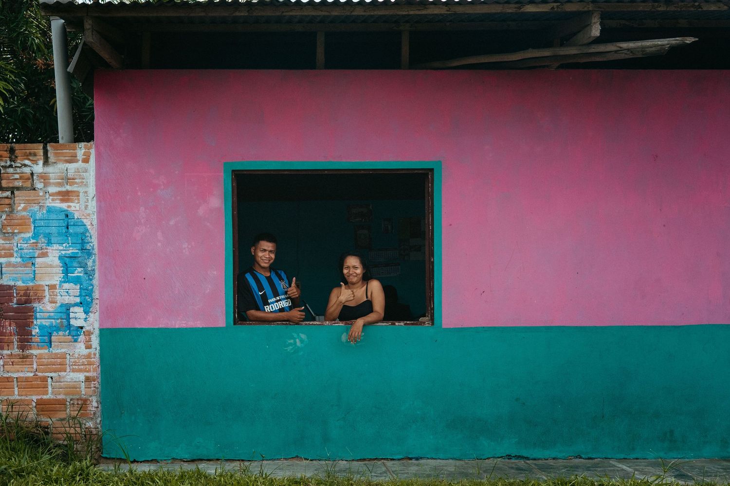 Pink and turquoise painted building wall with rectangular windows.